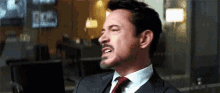 a man in a suit and tie is making a funny face while sitting in front of a computer .