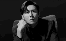 a man in a suit is sitting in a chair with his hand on his chin