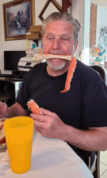 a man sitting at a table eating a large piece of crab