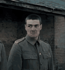 a man in a military uniform is making a funny face while standing in front of a brick building .