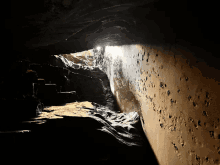 a dark cave with a light shining through a hole in the wall