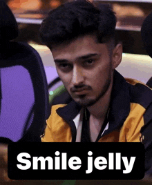 a man with a beard is sitting next to a sign that says smile jelly on it