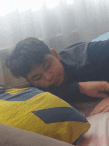 a boy is sleeping on a bed with a yellow and blue striped pillow