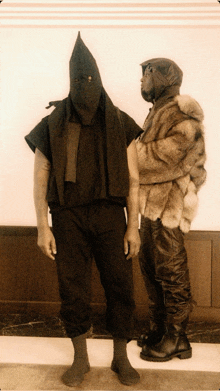 a man wearing a fur coat stands next to another man