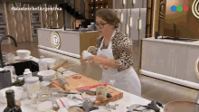 a woman in a white apron is standing in front of a counter with a cutting board and a knife on it ..