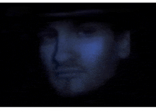 a close up of a man 's face with a blue light shining on his face .