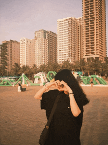 a girl making a heart shape with her hands in front of a building