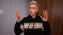 a man wearing a black sweater with a green white and red stripe with a g on it