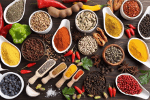 a wooden table topped with bowls and spoons of different spices .