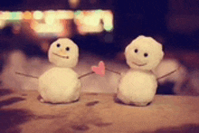 two snowmen are holding hands and a pink heart