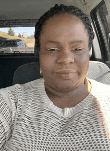 a woman wearing a white sweater is sitting in a car