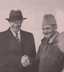 a man in a hat shakes hands with another man in a suit