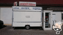 a white food truck is parked in front of a restaurant .