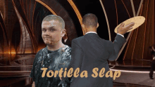 a man in a suit is holding a tortilla in front of a man in a messy shirt that says tortilla slap