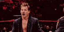 a wrestler is making a surprised face while sitting in a wrestling ring .
