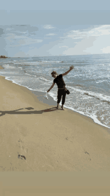 a person standing on a beach with their arms outstretched and their shadow on the sand