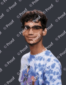 a young man wearing glasses and a blue tie dye shirt is standing in front of a proof watermark