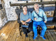 a man and a woman sit on a bench with a purse on their lap