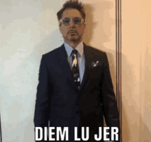 a man in a suit and tie is standing in front of a white wall with the words diem lu jer on it