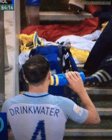 a man in a drinkwater jersey is drinking from a bottle