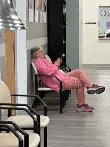 a woman in a pink shirt sits in a chair in a waiting room