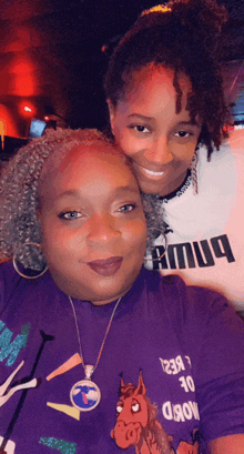 two women posing for a picture one wearing a purple shirt that says word