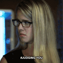 a woman wearing glasses has the hashtag #judging you written on her face