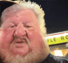 a man with a beard is standing in front of a yellow sign that says waffle house .