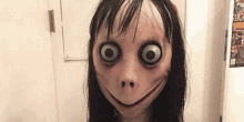 a woman wearing a scary mask with big eyes and a smile on her face .