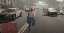 a woman in a pink sweater is walking down a street in front of a police car