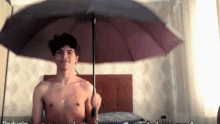 a shirtless man is holding an umbrella in front of a wall that says padusin