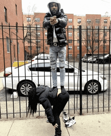 a man is standing on a woman 's shoulders in front of a car