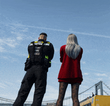 a man wearing a vest that says ' ount fire escli ' on it stands next to a woman