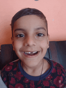 a young boy wearing a floral shirt is smiling with his mouth open