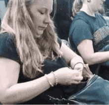 a woman is looking at her phone while sitting next to another woman .