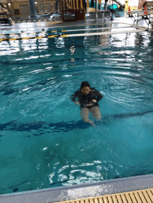 a woman is swimming in a swimming pool with a slide in the background