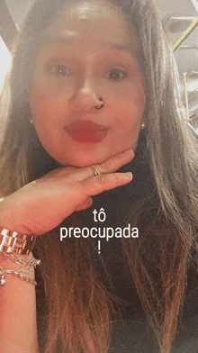 a woman with a nose ring holds her hand to her chin and says " to preocupada " in white letters