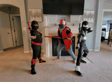 three children dressed up as ninjas and knights are standing in front of a fireplace in a living room