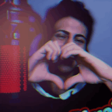 a blurry photo of a man making a heart with his hands