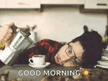 a man is laying on a counter with a cup of coffee and a coffee maker .