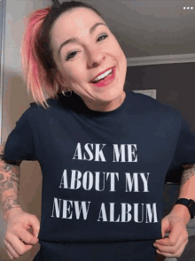 a woman wearing a t-shirt that says " ask me about my new album "