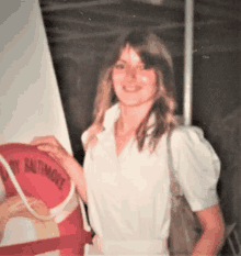 a woman in a white shirt holds a life preserver that says mary baltimore