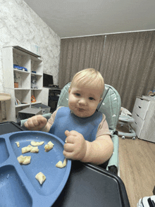 a baby sitting in a high chair with a blue plate of food