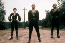 a group of people standing in a field with a cross in the background