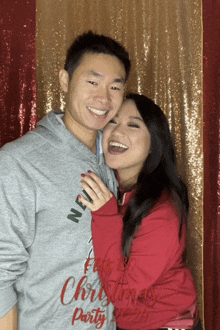 a man and a woman pose for a photo in front of a sequined curtain that says christmas party