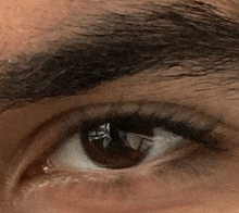 a close up of a person 's eye with a reflection of a person in it .