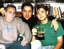 three men are posing for a picture and one has a shirt that says bottle