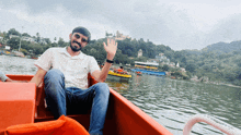 a man sits in a boat on a lake and waves