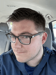 a man wearing glasses and a blue jacket is sitting in the back seat of a car