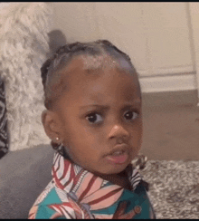 a little girl is making a funny face while sitting on a couch in a living room .